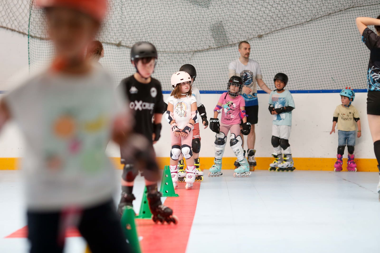 Peques de la escuela del CHL Meigas patinando con casco y protecciones en el pabellón