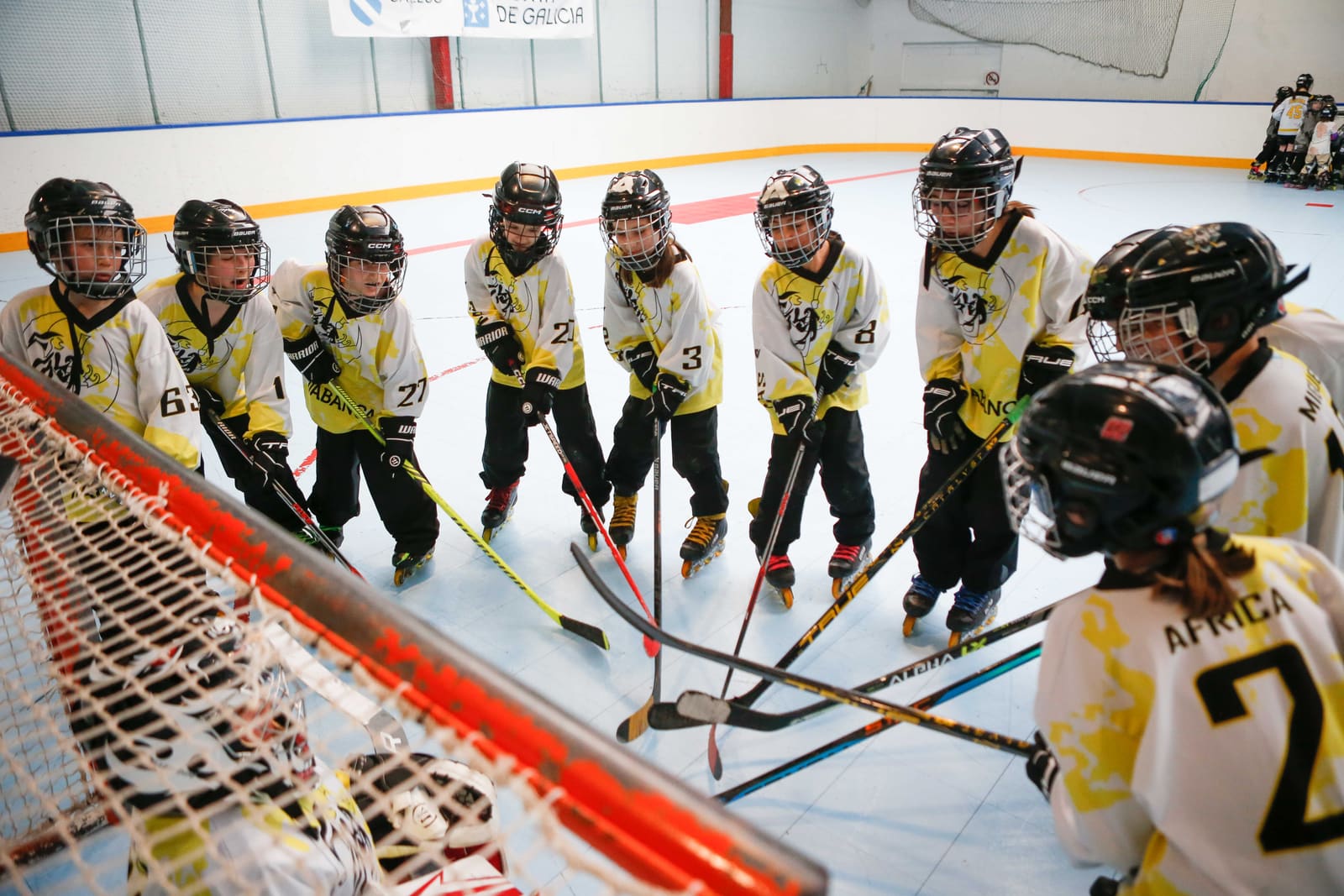 Cinco peques del CHL Meigas en equipación, con los sticks juntos sobre la portería